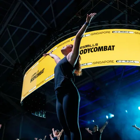 Instructor leading a Les Mills BODYCOMBAT class on stage in Singapore