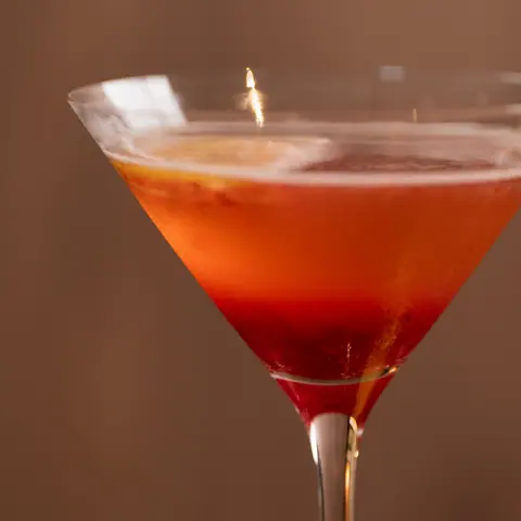 Orange-red cocktail in a coupe glass