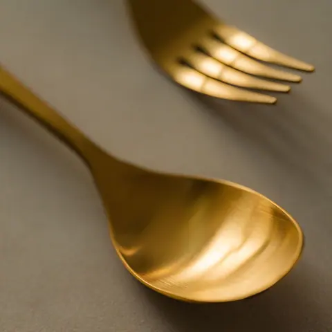 Gold spoon and fork on a muted background